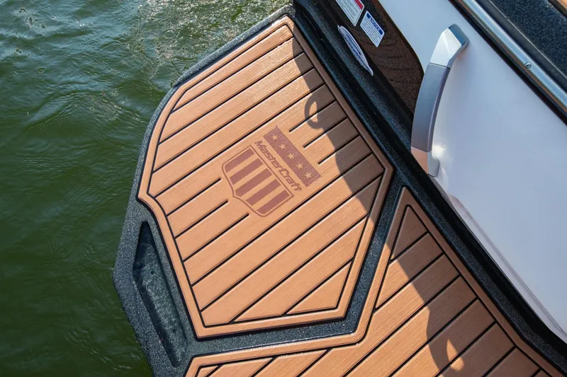 Slide: The Image of 2021 MasterCraft X22 boat swim platform with logo, near water. - 12