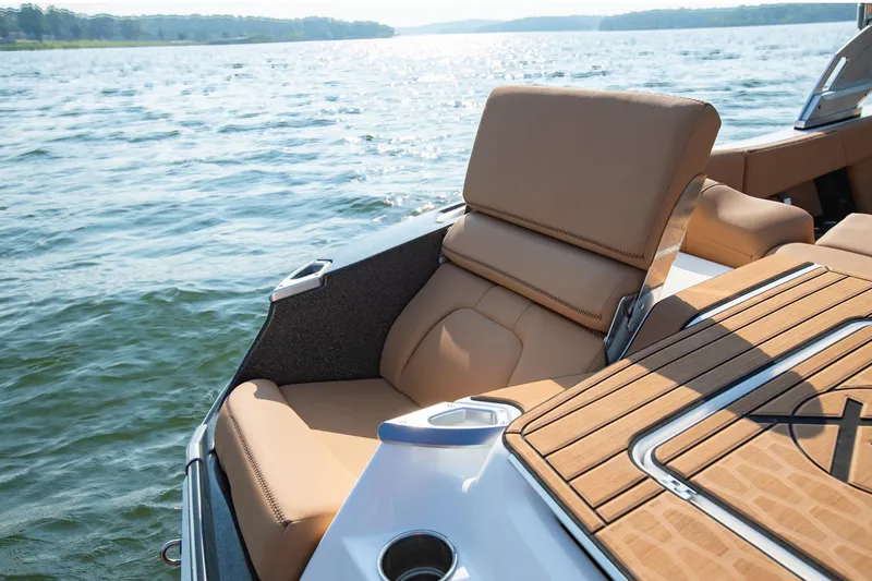 Slide: The Image of 2021 MasterCraft X22 boat with tan seating and wooden deck on a sunny lake. - 14