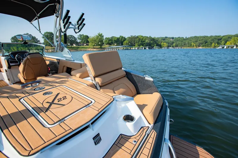 Slide: The Image of 2021 MasterCraft X22 boat interior with tan seating on a lake. - 15