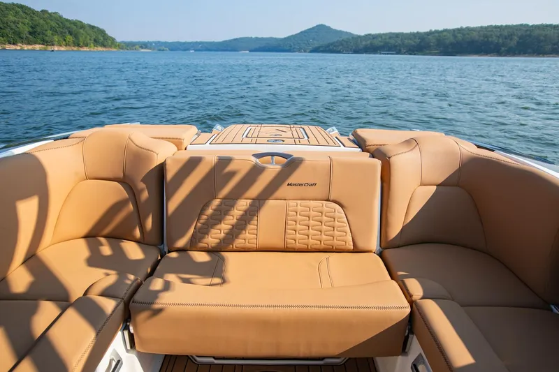 Slide: The Image of 2021 MasterCraft X22 boat interior with tan leather seats on a scenic lake. - 16