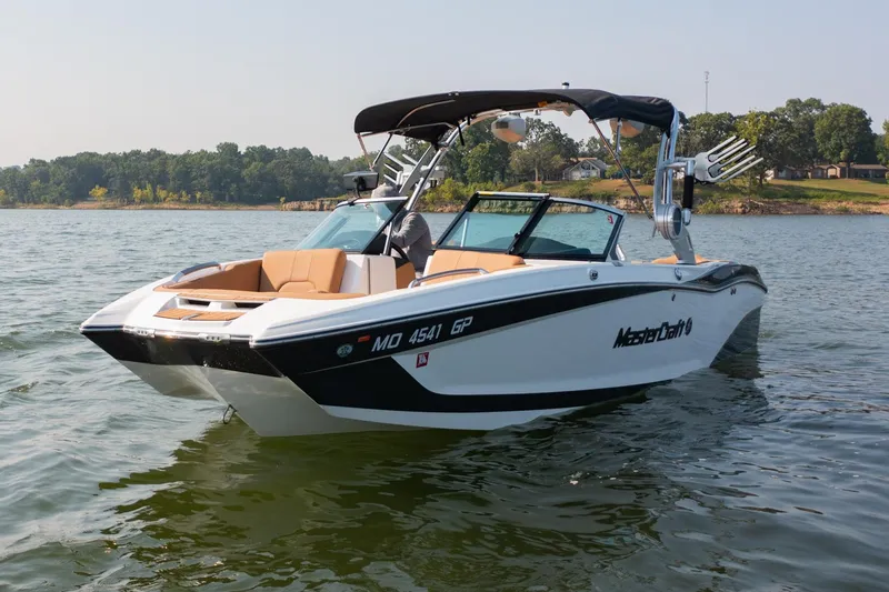 Slide: The Image of 2021 MasterCraft X22 boat on a lake, featuring sleek design and modern amenities. - 2
