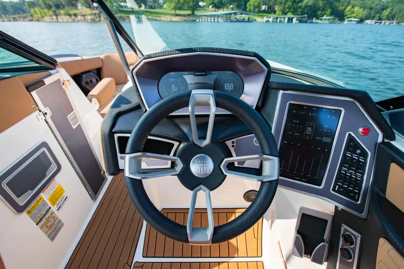 Slide: The Image of 2021 MasterCraft X22 boat dashboard with steering wheel and digital controls on a lake. - 21