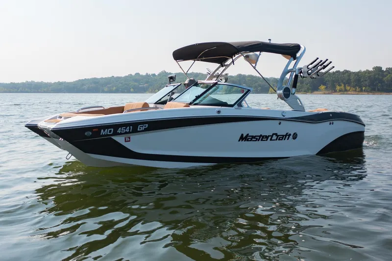 Slide: The Image of 2021 MasterCraft X22 boat on a calm lake, featuring sleek design and modern amenities. - 5