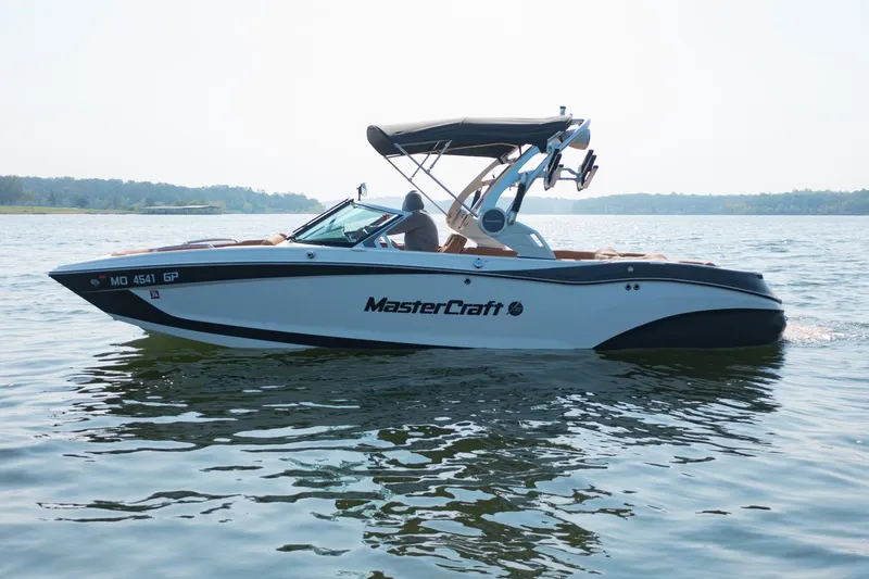 Slide: The Image of 2021 MasterCraft X22 boat cruising on a calm lake under clear skies. - 6