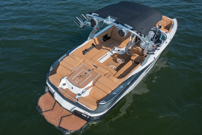 Slide: The Image of 2021 MasterCraft X22 boat with tan seating and black canopy on water. - 9