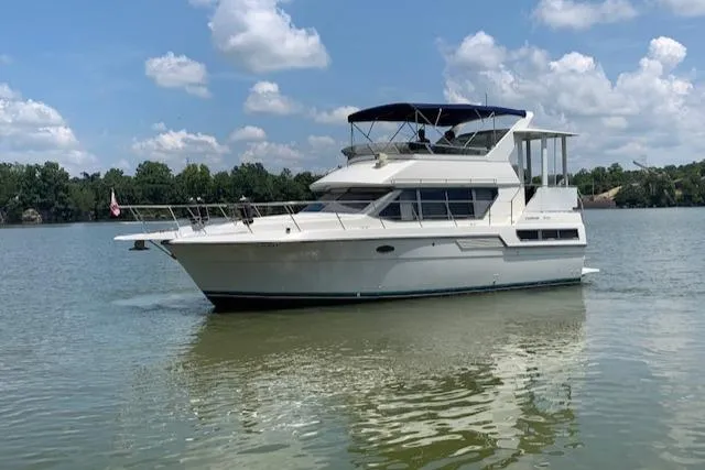 Slide: The Image of 1995 Carver 370 Aft Cabin yacht on a calm lake under a blue sky. - 0