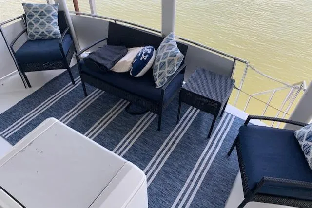 Slide: The Image of 1995 Carver 370 Aft Cabin deck with blue seating and striped rug, overlooking water. - 12