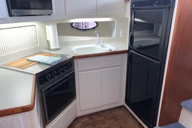 Slide: The Image of 1995 Carver 370 Aft Cabin kitchen with stove, sink, and refrigerator. - 17