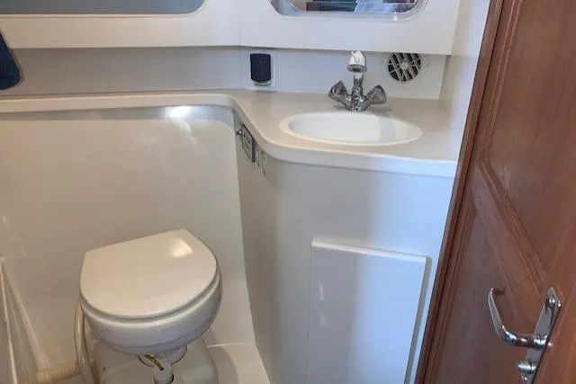 Slide: The Image of 1995 Carver 370 Aft Cabin bathroom with toilet, sink, and wooden door. - 19