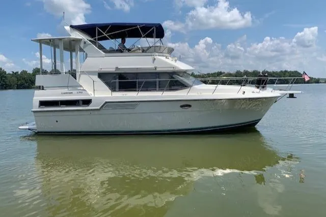 Slide: The Image of 1995 Carver 370 Aft Cabin yacht on calm water under a blue sky. - 2