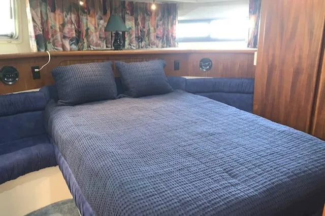 Slide: The Image of 1995 Carver 370 Aft Cabin bedroom with blue bedding and wood accents. - 20