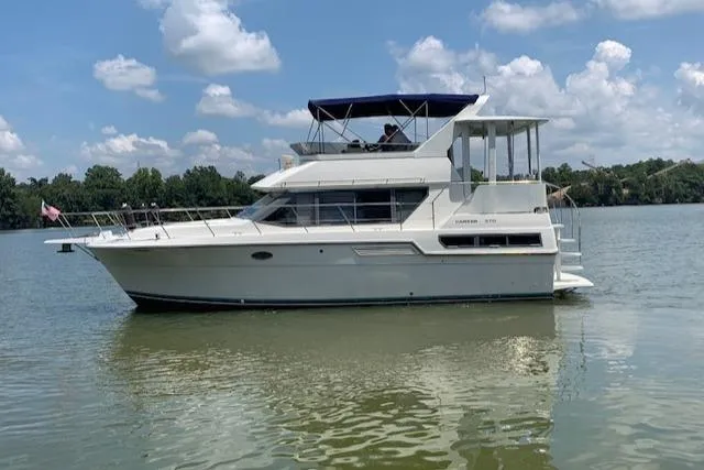 Slide: The Image of 1995 Carver 370 Aft Cabin yacht on a calm lake under a blue sky. - 3