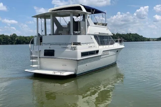 Slide: The Image of 1995 Carver 370 Aft Cabin yacht on calm water under a blue sky. - 4