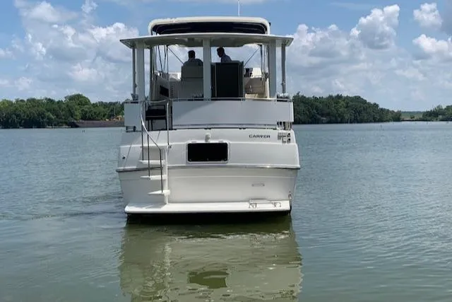 Slide: The Image of 1995 Carver 370 Aft Cabin boat on calm lake under blue sky. - 6