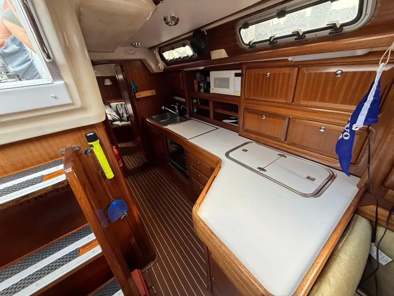 Slide: The Image of Interior of 1999 Bavaria 42 Ocean yacht with wooden cabinetry and compact kitchen area. - 28