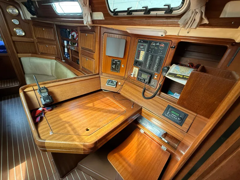 Slide: The Image of Navigation station inside 1999 Bavaria 42 Ocean yacht, featuring control panels and wooden cabinetry. - 30