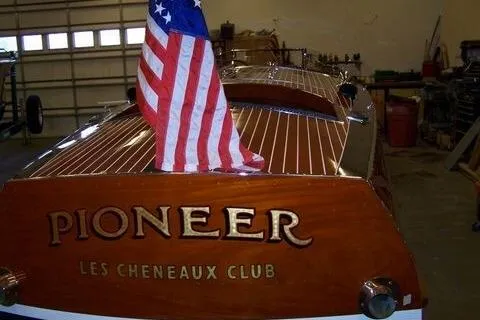Slide: The Image of 1931 Hacker-Craft 26 Dolphin boat with American flag, labeled "Pioneer" and "Les Cheneaux Club." - 105