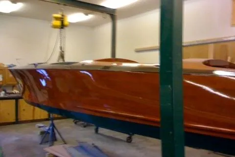 Slide: The Image of 1931 Hacker-Craft 26 Dolphin boat in workshop, showcasing polished wooden hull. - 224