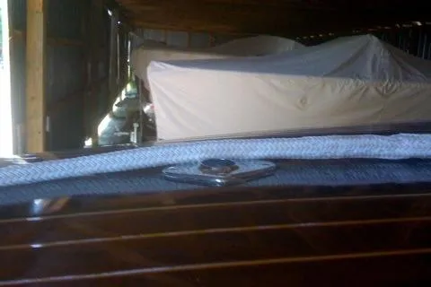 Slide: The Image of 1931 Hacker-Craft 26 Dolphin boat in storage, partially covered, showcasing wooden detailing. - 230