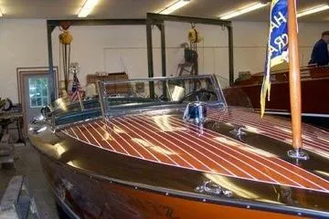 Slide: The Image of 1931 Hacker-Craft 26 Dolphin boat with polished wood finish in a workshop. - 28