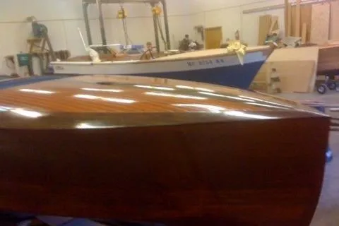 Slide: The Image of 1931 Hacker-Craft 26 Dolphin boat with polished wooden hull in workshop setting. - 37