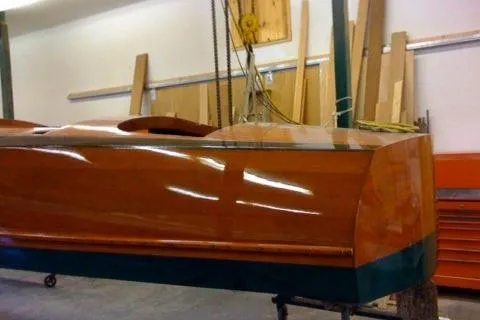 Slide: The Image of 1931 Hacker-Craft 26 Dolphin boat in workshop, showcasing polished wooden hull. - 54