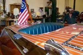 Slide: The Image of 1931 Hacker-Craft 26 Dolphin boat with American flag in workshop setting. - 60