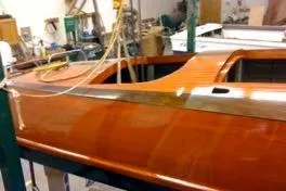 Slide: The Image of 1931 Hacker-Craft 26 Dolphin boat with polished wooden finish in a workshop setting. - 76