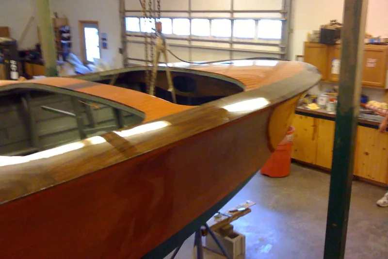 Slide: The Image of 1931 Hacker-Craft 26 Dolphin boat in a workshop, showcasing its polished wooden hull. - 85