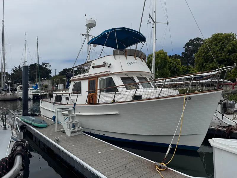 The Image of 1984 Monk 36 Trawler docked at marina, featuring classic design and blue canopy. - 0