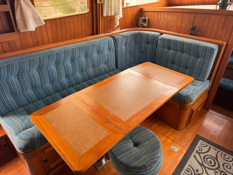 Slide: The Image of 1984 Monk 36 Trawler interior with blue upholstered seating and wooden dining table. - 11