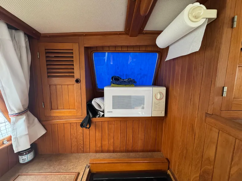 Slide: The Image of 1984 Monk 36 Trawler interior with microwave, wooden cabinetry, and paper towel holder. - 15