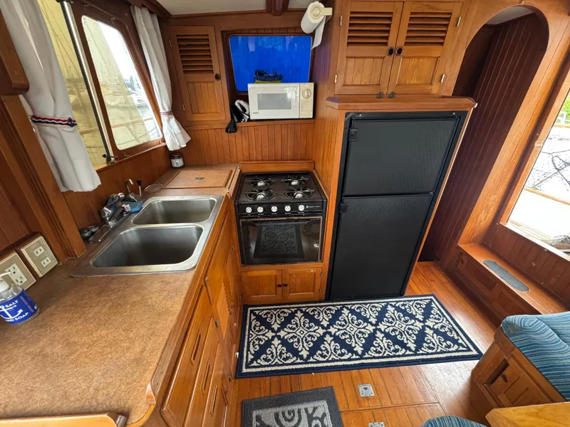 Slide: The Image of 1984 Monk 36 Trawler kitchen with wood cabinetry, dual sinks, stove, and refrigerator. - 16