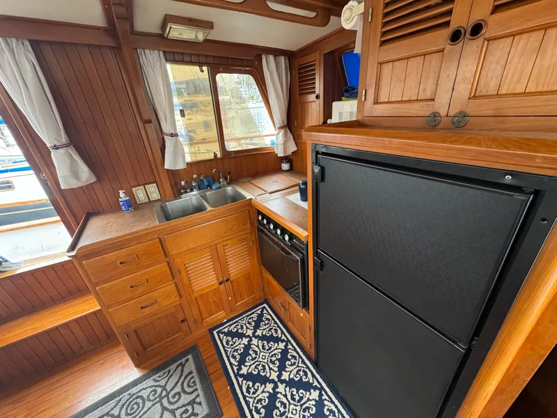 Slide: The Image of 1984 Monk 36 Trawler kitchen with wood cabinetry, double sink, and black refrigerator. - 17