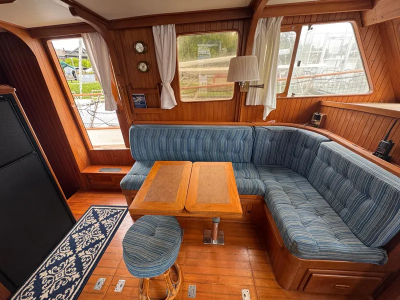 Slide: The Image of Interior of 1984 Monk 36 Trawler with blue seating, wooden table, and nautical decor. - 18