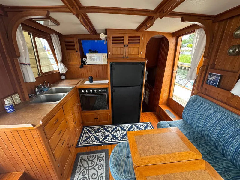 Slide: The Image of Interior of 1984 Monk 36 Trawler with wood paneling, kitchenette, and seating area. - 19