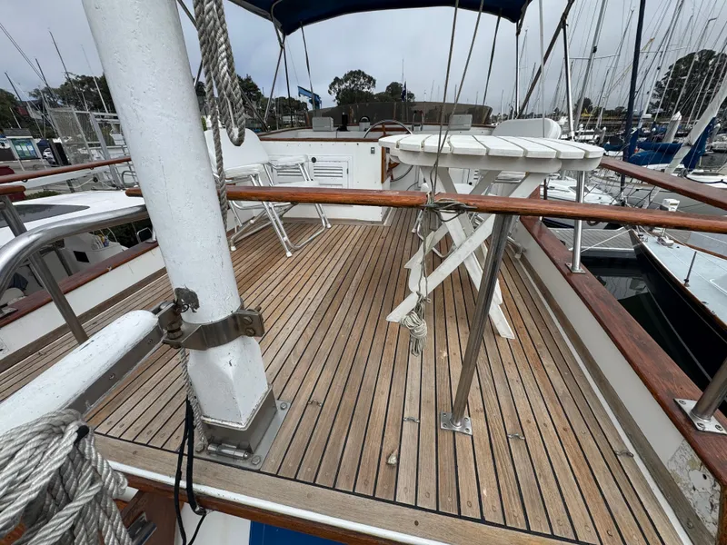 Slide: The Image of 1984 Monk 36 Trawler deck with wooden flooring and white folding chairs. - 3