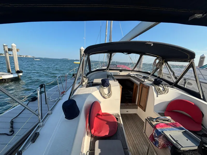 Slide: The Image of 2014 Bavaria 36 Cruiser sailboat docked, featuring a spacious cockpit with red cushions. - 24