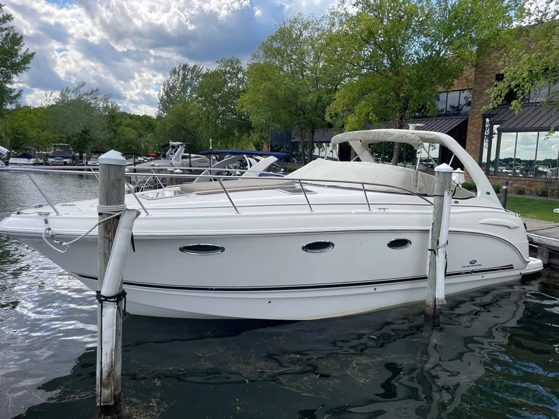 The Image of 2005 Chaparral Signature 330 boat docked by a lakeside with trees and buildings. - 0