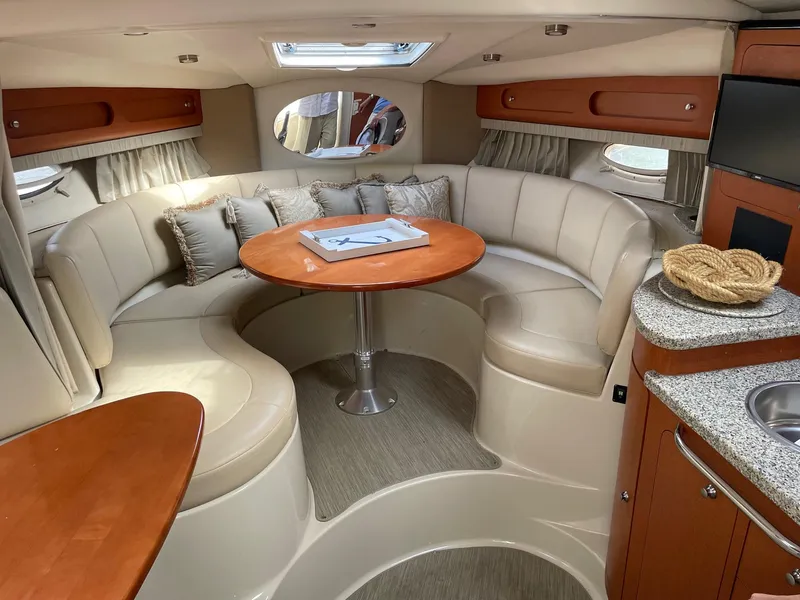 Slide: The Image of 2005 Chaparral Signature 330 interior with curved seating, wooden table, and kitchenette. - 13