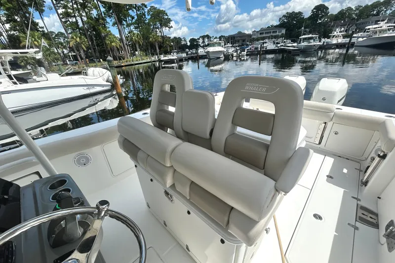 Slide: The Image of 2017 Boston Whaler 330 Outrage boat interior with luxurious seating in a marina setting. - 11