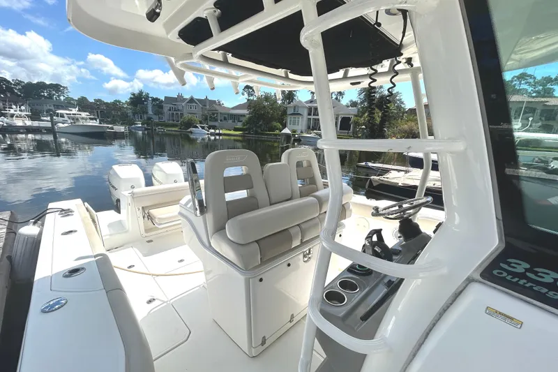 Slide: The Image of 2017 Boston Whaler 330 Outrage boat interior with seating and helm, docked in a marina. - 12