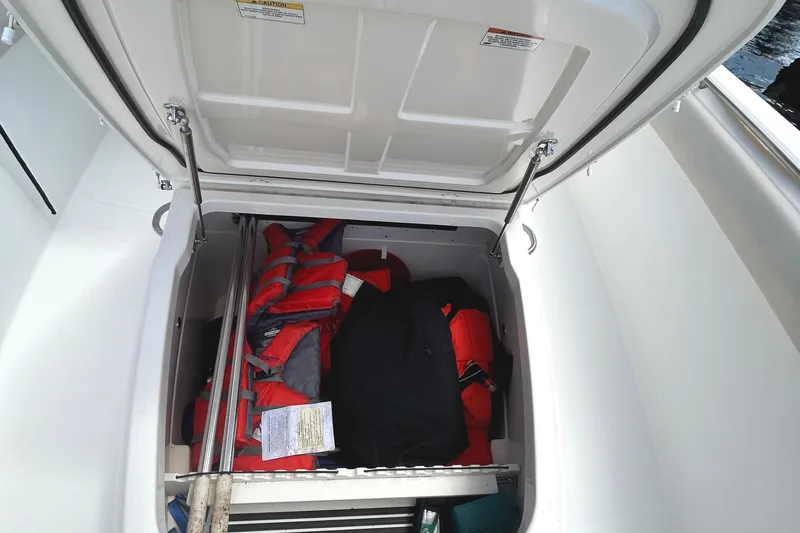 Slide: The Image of Open storage compartment on 2017 Boston Whaler 330 Outrage, containing life jackets and gear. - 34