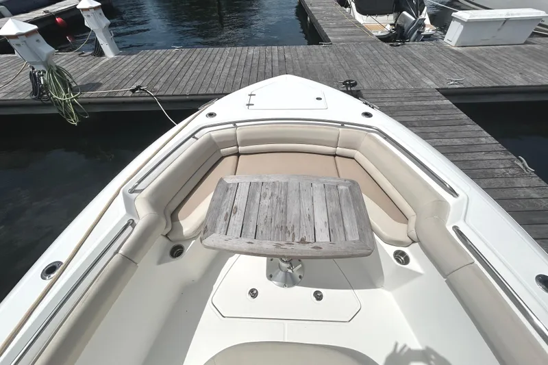 Slide: The Image of 2017 Boston Whaler 330 Outrage boat with cushioned seating and wooden table at dock. - 6