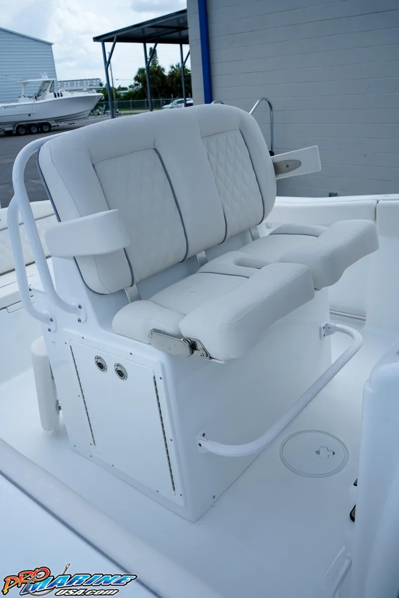 Slide: The Image of 2026 Sea Hunt Ultra 255 SE boat seating, white cushioned helm seats, outdoor marina setting. - 13