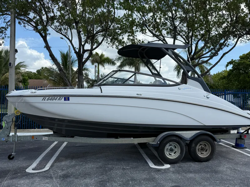 Slide: The Image of 2017 Yamaha Boats 212 Limited S on trailer, parked outdoors with trees in background. - 2