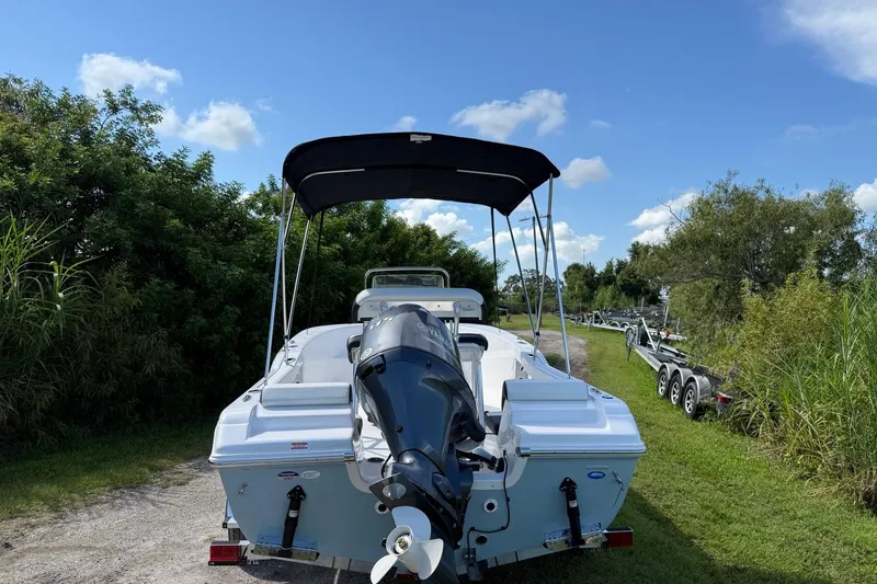 Slide: The Image of 2026 Tidewater 180 CC Adventure boat with outboard motor and canopy, parked on grassy path. - 12
