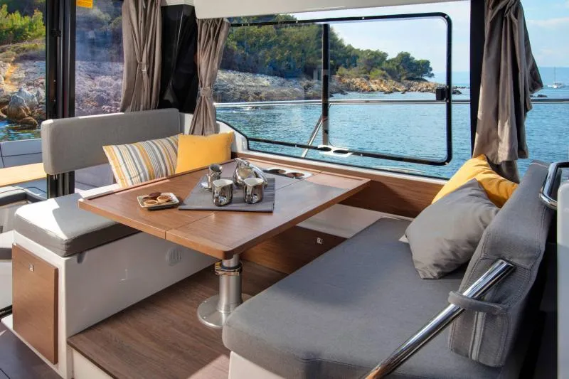 Slide: The Image of 2026 Jeanneau NC 1095 boat interior with seating, table, and decorative pillows. - 5