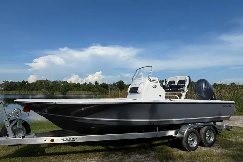 The Image of 2026 Tidewater 2110 Bay Max boat on trailer by a lake under blue sky. - 0