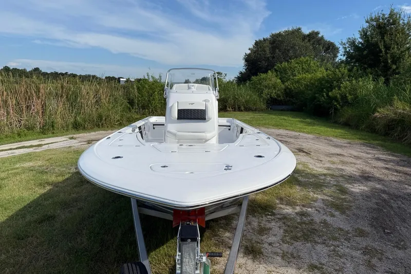 Slide: The Image of 2026 Tidewater 2110 Bay Max boat on trailer, surrounded by lush greenery. - 11